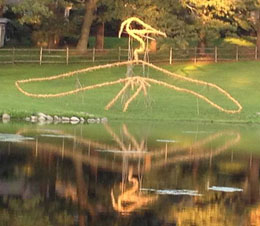 Burlap-wrapped, wood-frame outline of a heron (seen across a lake)