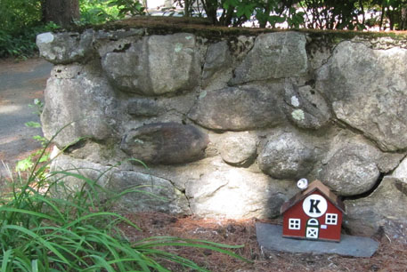 A small house in front of a stone wall