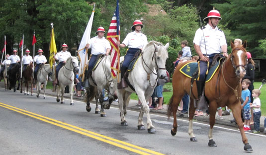 A parade of horses, riders carrying flags
