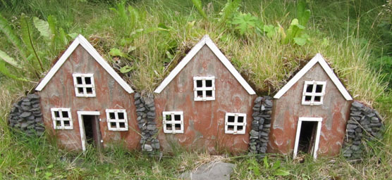 3 miniature houses set into a sod mound