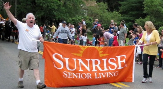 Banner from a local senior residence, held by marcher waving enthusiastically