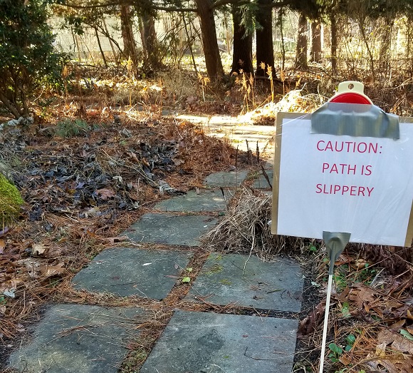 Path to the sunroom with a sign reading 'CAUTION: PATH IS SLIPPERY'