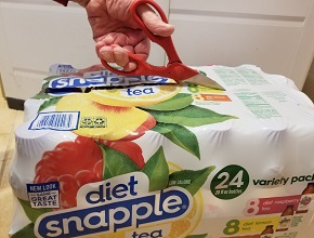 Larry carefully opening a Snapple pack with scissors